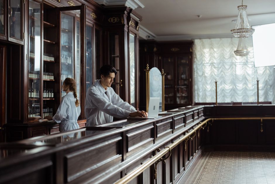 Pharmacists working in a vintage pharmacy setting with old-fashioned decor.